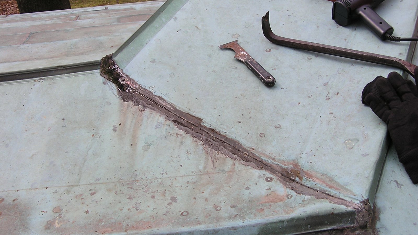 Copper roof leaking flat seam with tar and caulking before repair